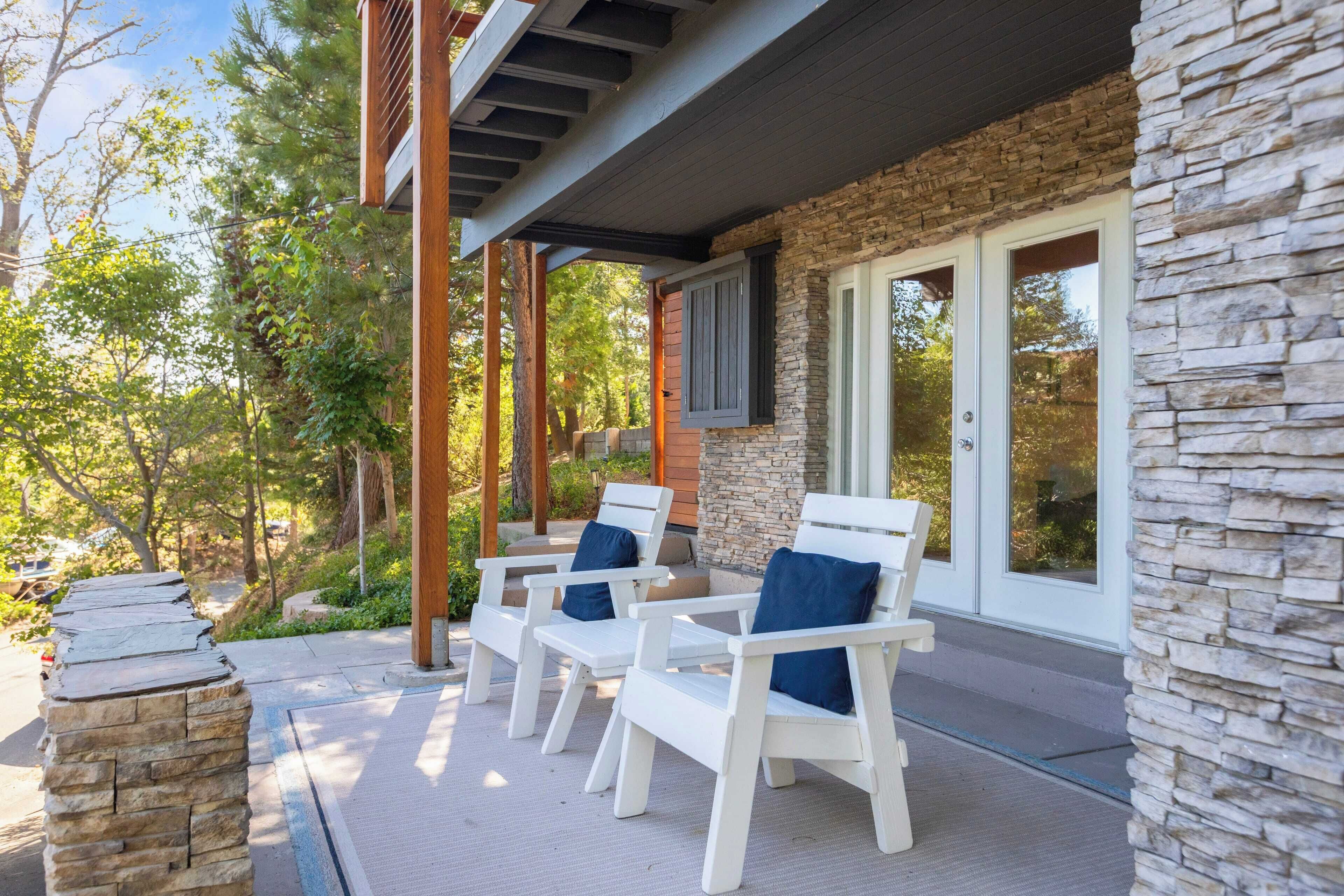 A covered patio with white chairs and stone accents.
