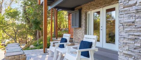 A covered patio with white chairs and stone accents.