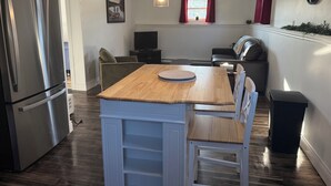 Una cocina moderna con una isla de madera, electrodomésticos de acero inoxidable y un comedor con televisor.