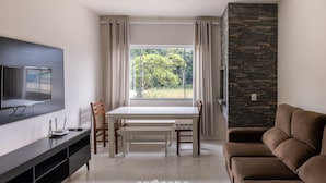 Un salon moderne doté d’un téléviseur à écran plat, d’une table à manger avec des chaises, d’un canapé marron et d’un mur décoratif en pierre.