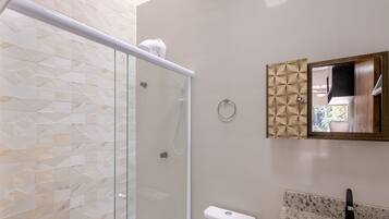 Un baño moderno con cabina de ducha de vidrio, inodoro y lavamanos con encimera de granito.