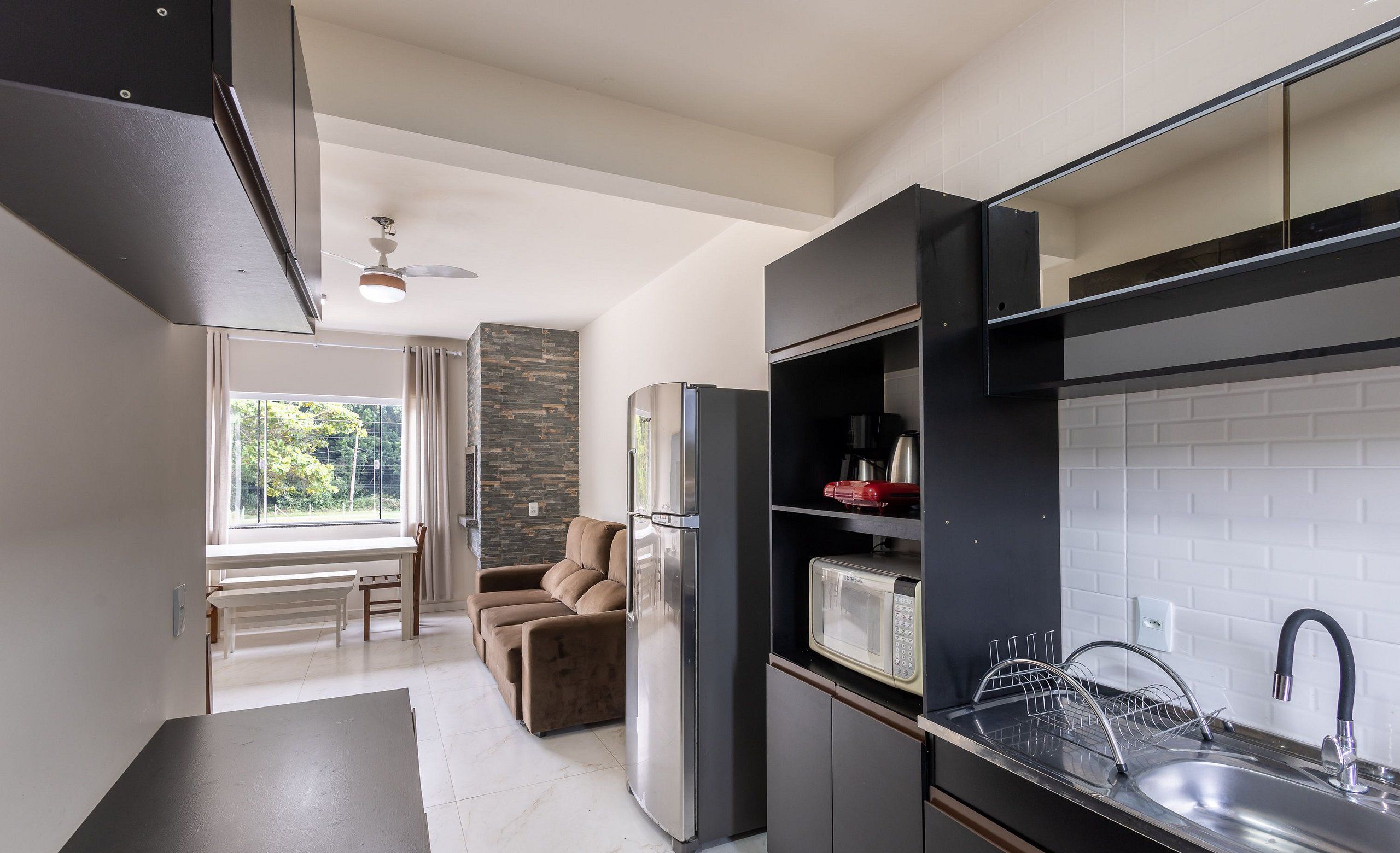A modern kitchen with a built-in microwave, stainless steel sink, and a refrigerator.