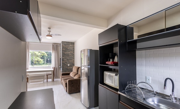A modern kitchen with a built-in microwave, stainless steel sink, and a refrigerator.
