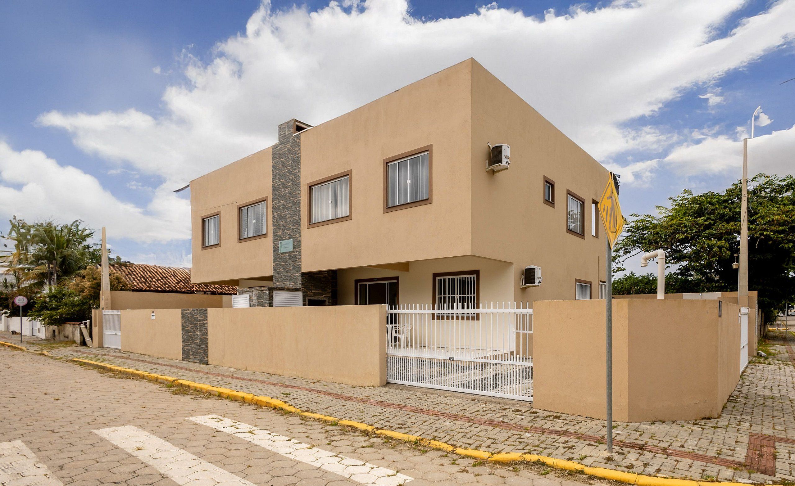 Un edificio moderno de dos pisos con techo plano, ventanas amplias y entrada con portón.