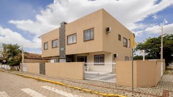 Un edificio moderno de dos pisos con techo plano, ventanas amplias y entrada con portón.