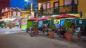 An outdoor seating area with tables and chairs, surrounded by potted plants and umbrellas.