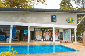 A building with a swimming pool, a sign for 'Borneo Divers Sabah', and a 'Dive Safe with Mamu Island' poster. - Mamutik Island Lodge (Mamutik Island)