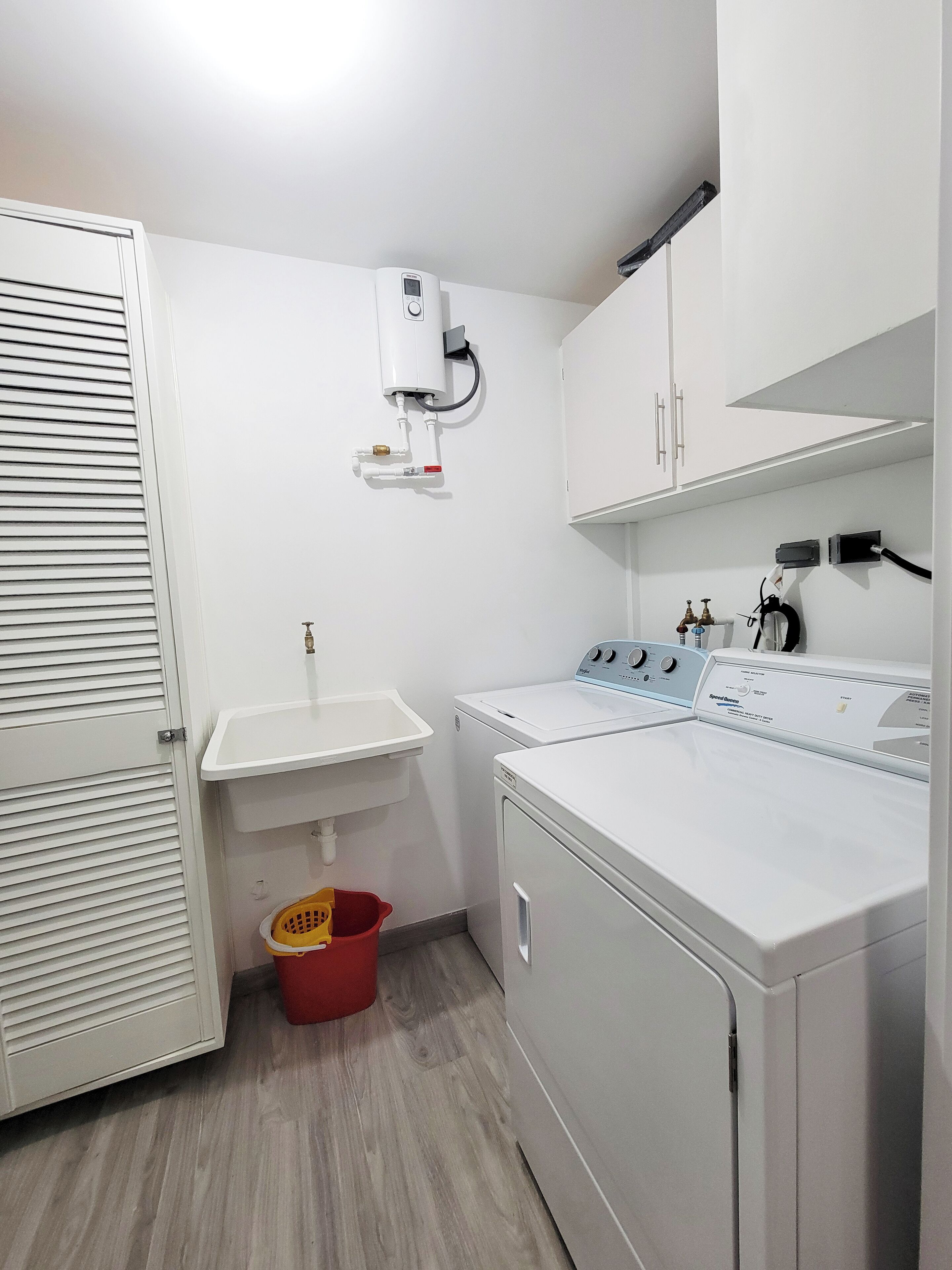Un cuarto de lavandería con lavadora, lavadero y calentador de agua.