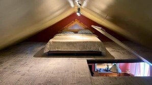A small, triangular attic bedroom with a single bed, sloped ceilings, and a skylight. - The Moose Lodge on the Susquehanna River (Sugar Run)