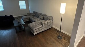 Ein Wohnzimmer mit einem Ecksofa, einem Couchtisch und einer Stehlampe.
