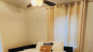 Quarto com cama, ventilador de teto e cortinas.