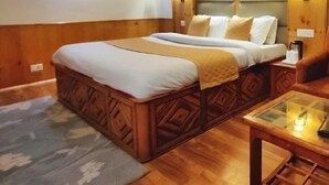 A wooden-paneled room with a bed, a nightstand, and a table with a lamp. - Hotel Surya International - Manali (Manali)