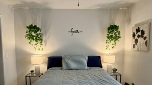 A bedroom with a bed, two bedside tables, two lamps, a wall-mounted plant, a wall-mounted artwork, and a ceiling light fixture. - 3rd Ward Gem: Modern Comfort + History (Houston)