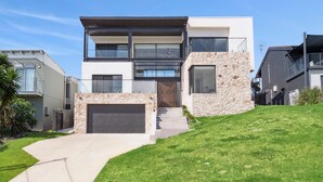 Una casa moderna de dos pisos con fachada de piedra, ventanas grandes y garaje.