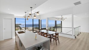 Una cocina moderna con una isla grande, sillas de madera y vistas al océano.