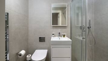 A modern bathroom with a toilet, sink, and shower.