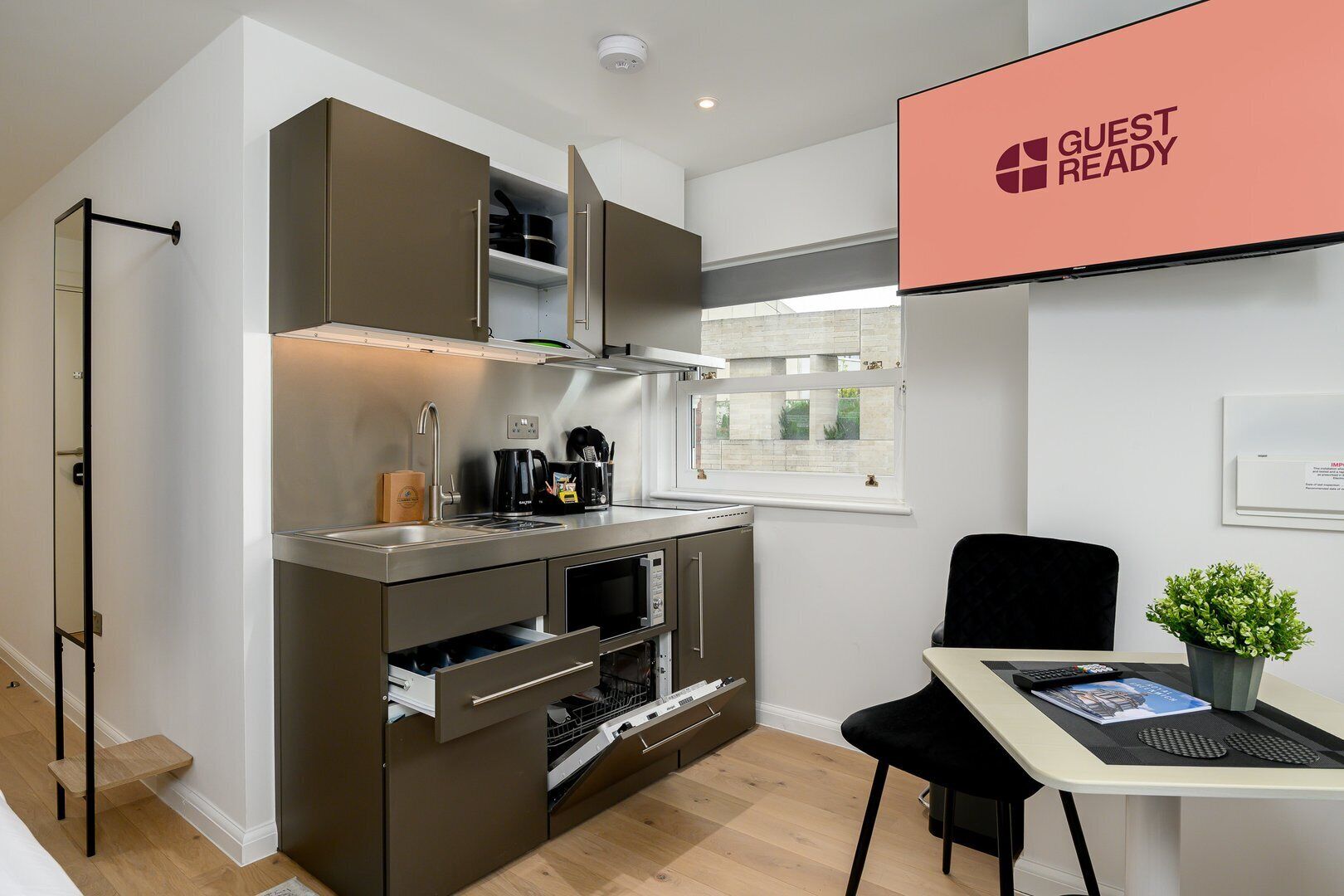 A compact kitchen with built-in appliances, a dining area with a table and chairs, and a window with a view.
