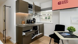 Una cucina compatta con elettrodomestici moderni, una zona pranzo con tavolo e sedia, e una finestra vista.