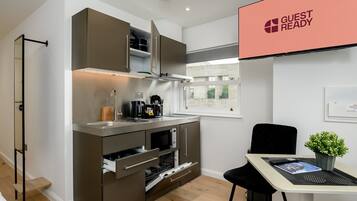 A compact kitchen with built-in appliances, a dining area with a table and chairs, and a window with a view.