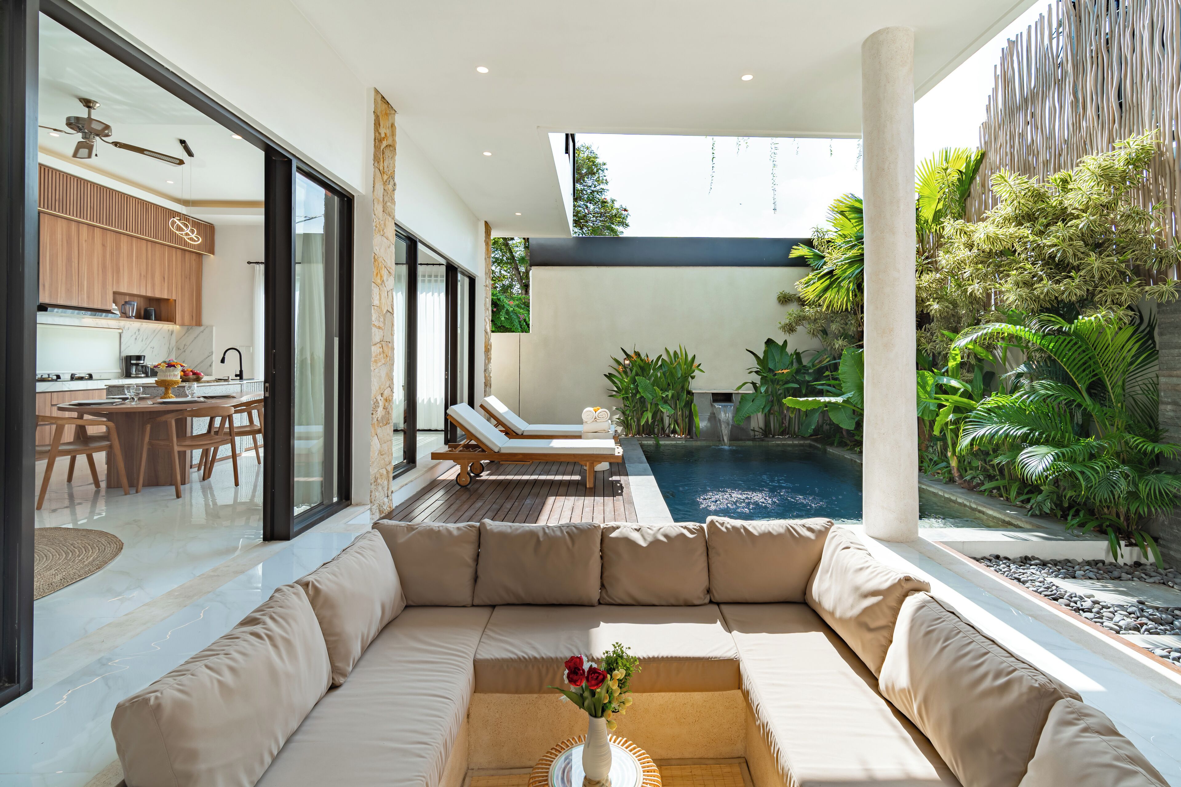 A modern living area with a large sofa, a dining table, and a kitchen in the background.