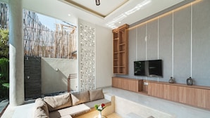 A modern living room with a sectional sofa, a flat-screen TV, and a wooden cabinet.