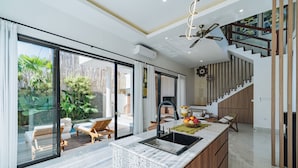 A modern kitchen with a large island, a dining area with a view, and a staircase leading to an upper level.