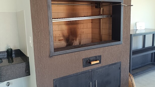 Una cocina moderna con horno empotrado, una encimera con fregadero y un armario debajo. Hay dos bolsas de carbón en el suelo.