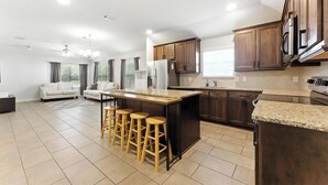 Una cocina moderna con armarios de madera oscura, encimera de granito y una isla central con taburetes.