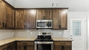 Una cocina con armarios de madera, un microondas de acero inoxidable y un horno.