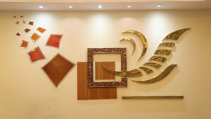 Een muur met verschillende geometrische en abstracte kunstwerken, waaronder een opvallend gouden, gebogen ontwerp.