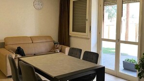 A dining area with a table and chairs, a sofa, and a window with a view. - Poetto di Cagliari vacation home 2 steps from the sea, relax sport and fun (Cagliari)