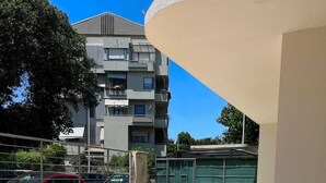 A balcony with tiled flooring, a railing, and a view of a multi-story building in the background. - Poetto di Cagliari vacation home 2 steps from the sea, relax sport and fun (Cagliari)