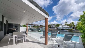 Une terrasse extérieure moderne avec une piscine, des chaises longues et un espace repas.