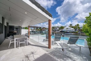 A modern outdoor patio with a pool, lounge chairs, and a dining area.