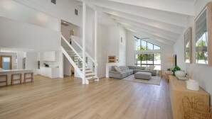 Un vaste espace de vie comprenant un escalier, un grand canapé et un coin repas.