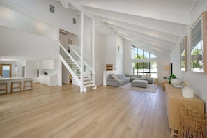 A spacious living area with a staircase, a large sofa, and a dining area.