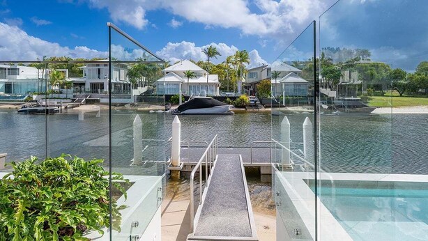 Un hôtel moderne doté d’une piscine, de rampes en verre et offrant une vue sur l’eau.