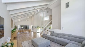 Un salon spacieux avec un grand canapé d’angle gris, une table basse en bois et un tapis à motifs.
