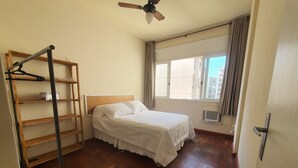 Un dormitorio con una cama, una escalera de madera, una ventana con cortinas y un ventilador de techo.