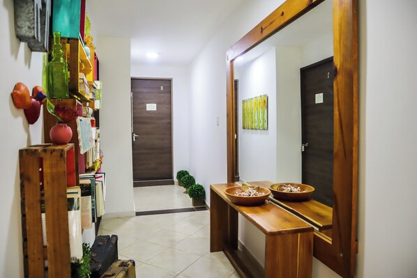 A hallway with a wooden bench, a mirror, and a door marked with the number 3. - Casa La Condesa (Cartagena)