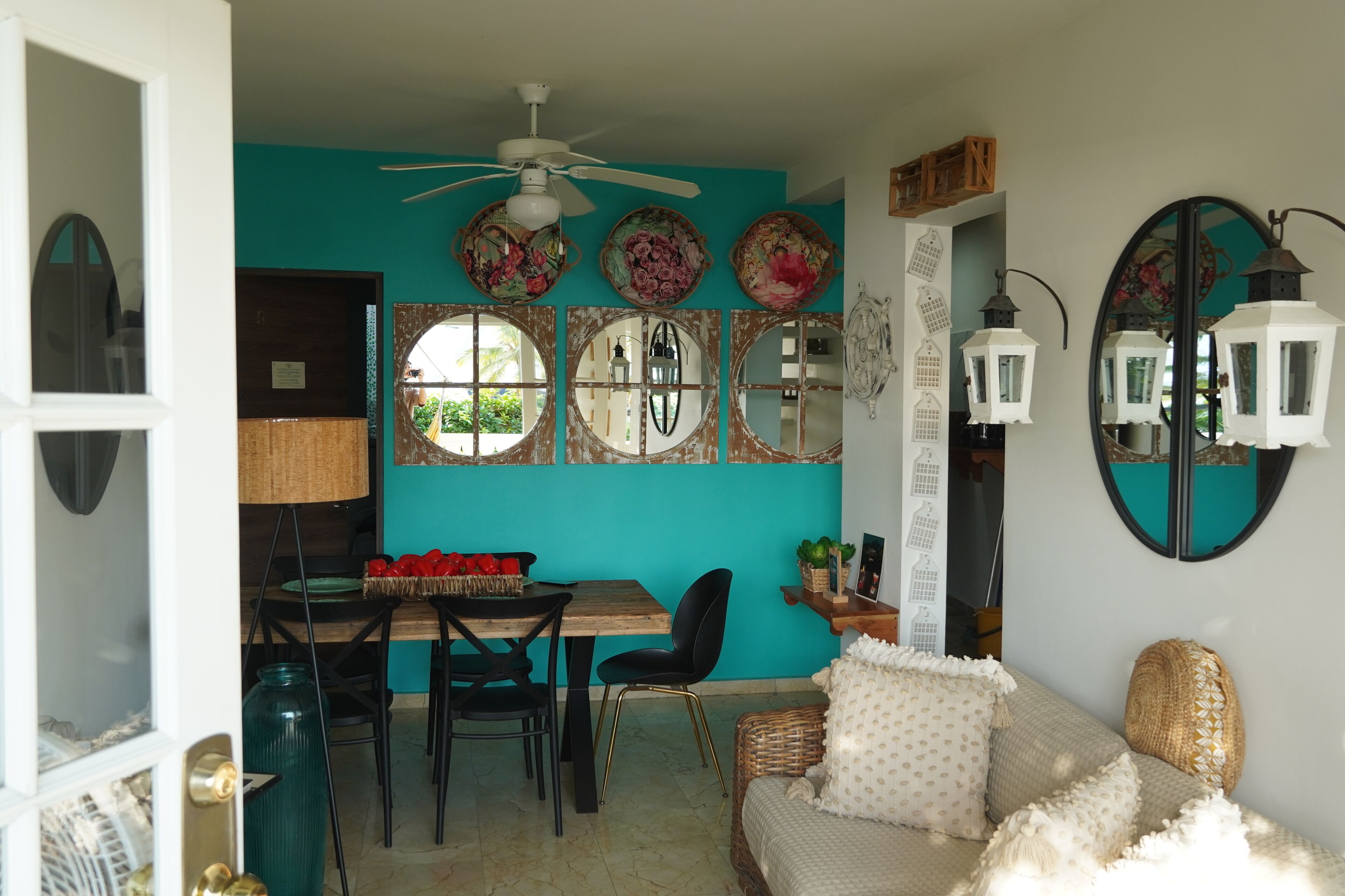 A dining area with a wooden table and chairs, a ceiling fan, and decorative wall mirrors.