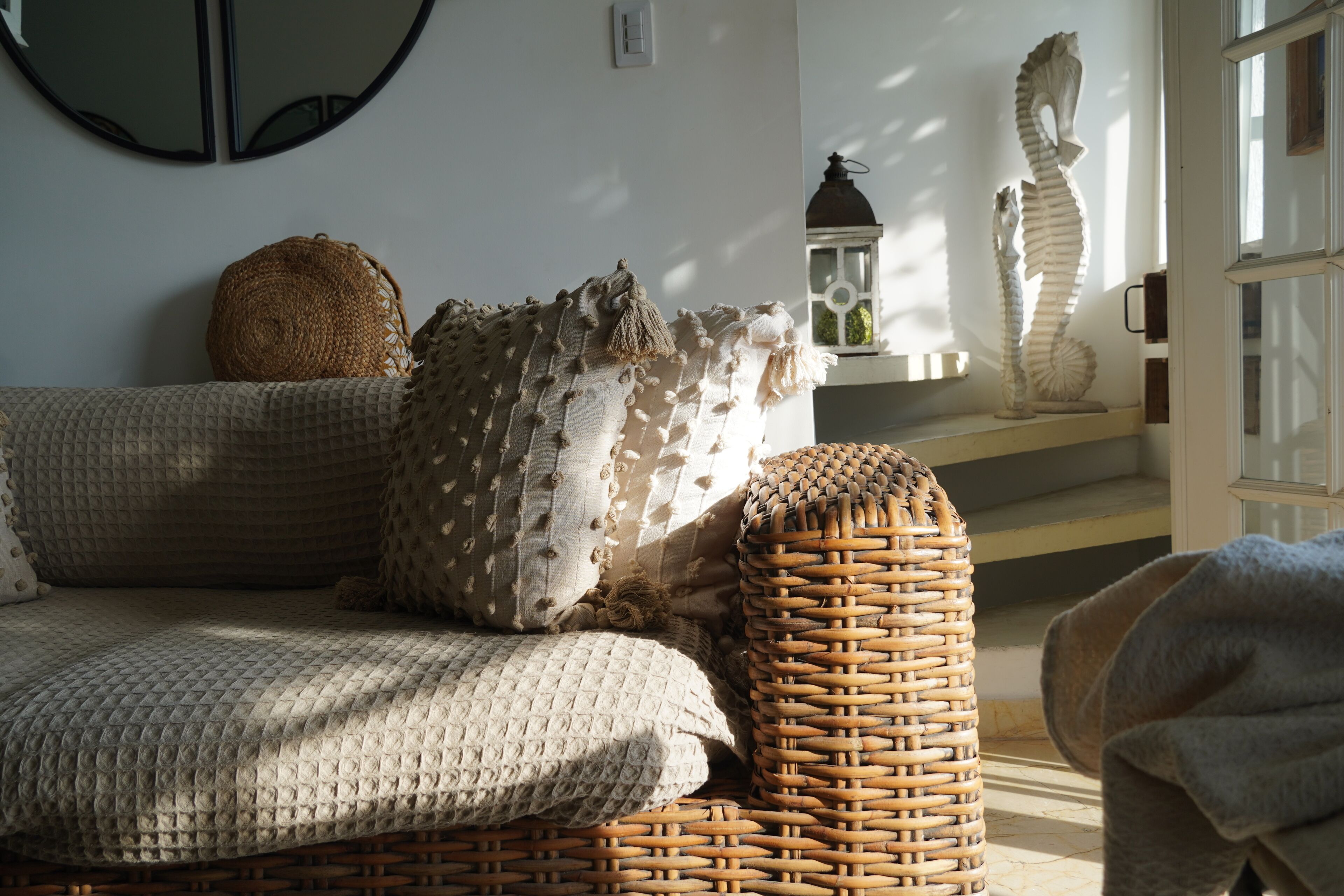 Uma sala de estar aconchegante com um sofá trançado, uma almofada estampada e uma escultura decorativa de cavalo-marinho.