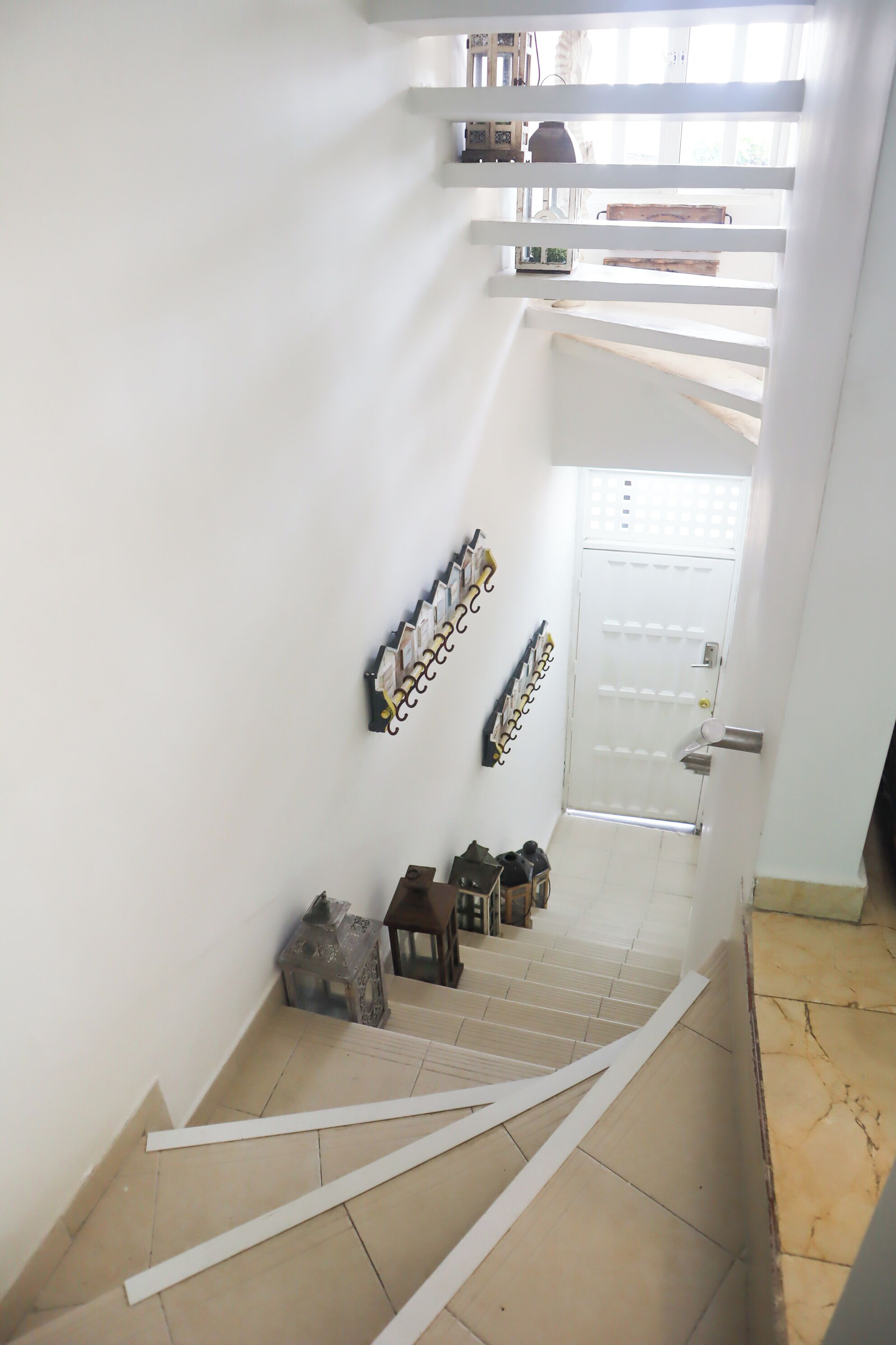 Eine Treppe mit weißen Geländern, eine weiße Tür oben und ein gefliestes Podest.