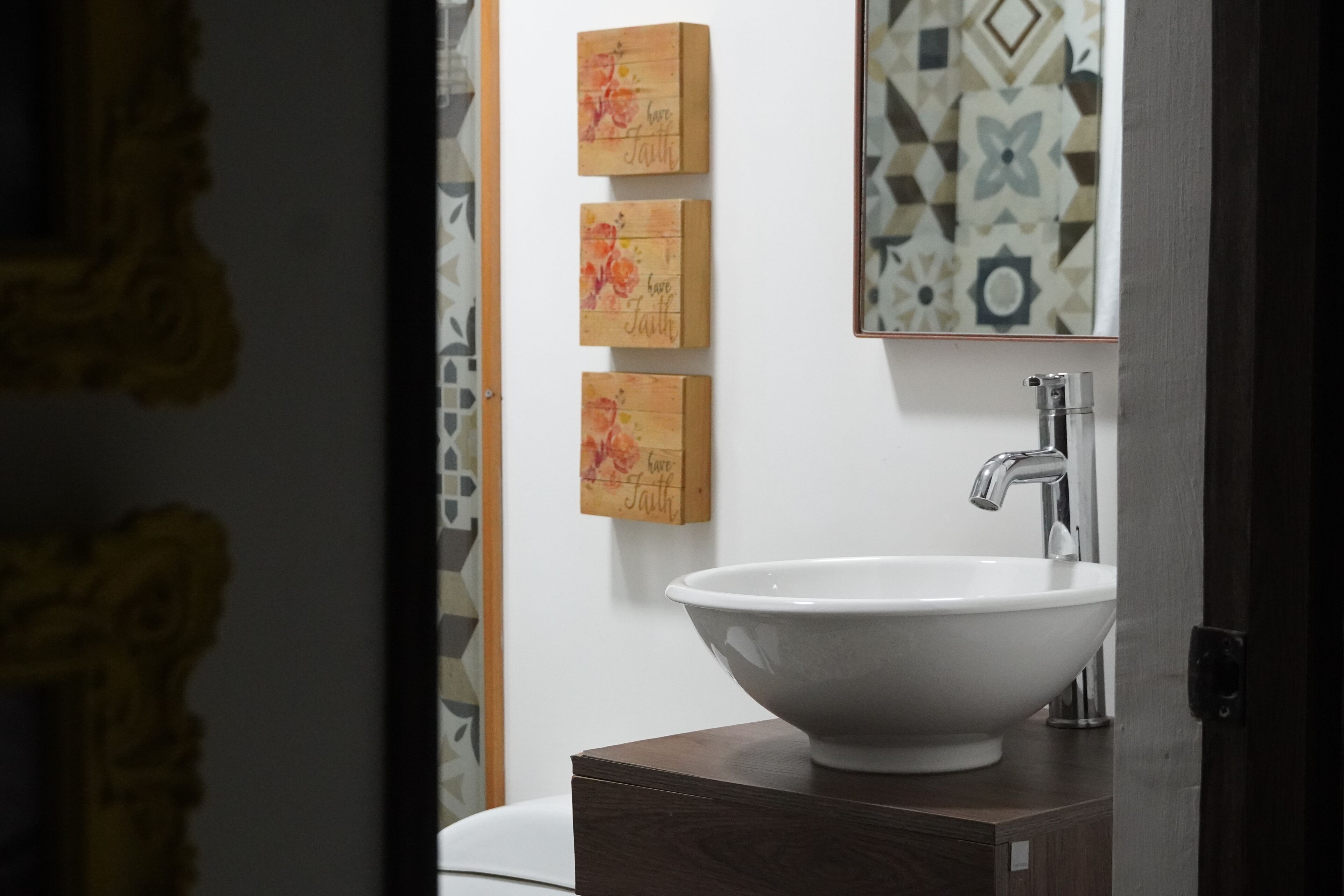 A bathroom with a white sink, a mirror, and three wooden signs with the phrase "have faith."