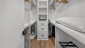 A compact, well-organized closet with multiple shelves, hanging space, and a foldable bed. - Stay Local Fantastic 4 Bedroom Near the Rez Sleeps 16 (Brandon)