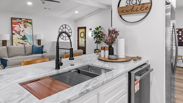 A modern kitchen with a marble countertop, stainless steel sink, and a built-in dishwasher. - Stay Local Fantastic 4 Bedroom Near the Rez Sleeps 16 (Brandon)