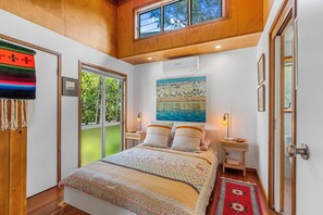Een slaapkamer met een groot bed, een schilderij, een raam en een deur.