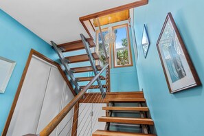 A staircase with wooden steps and metal railings, leading to a landing with a window and a door.
