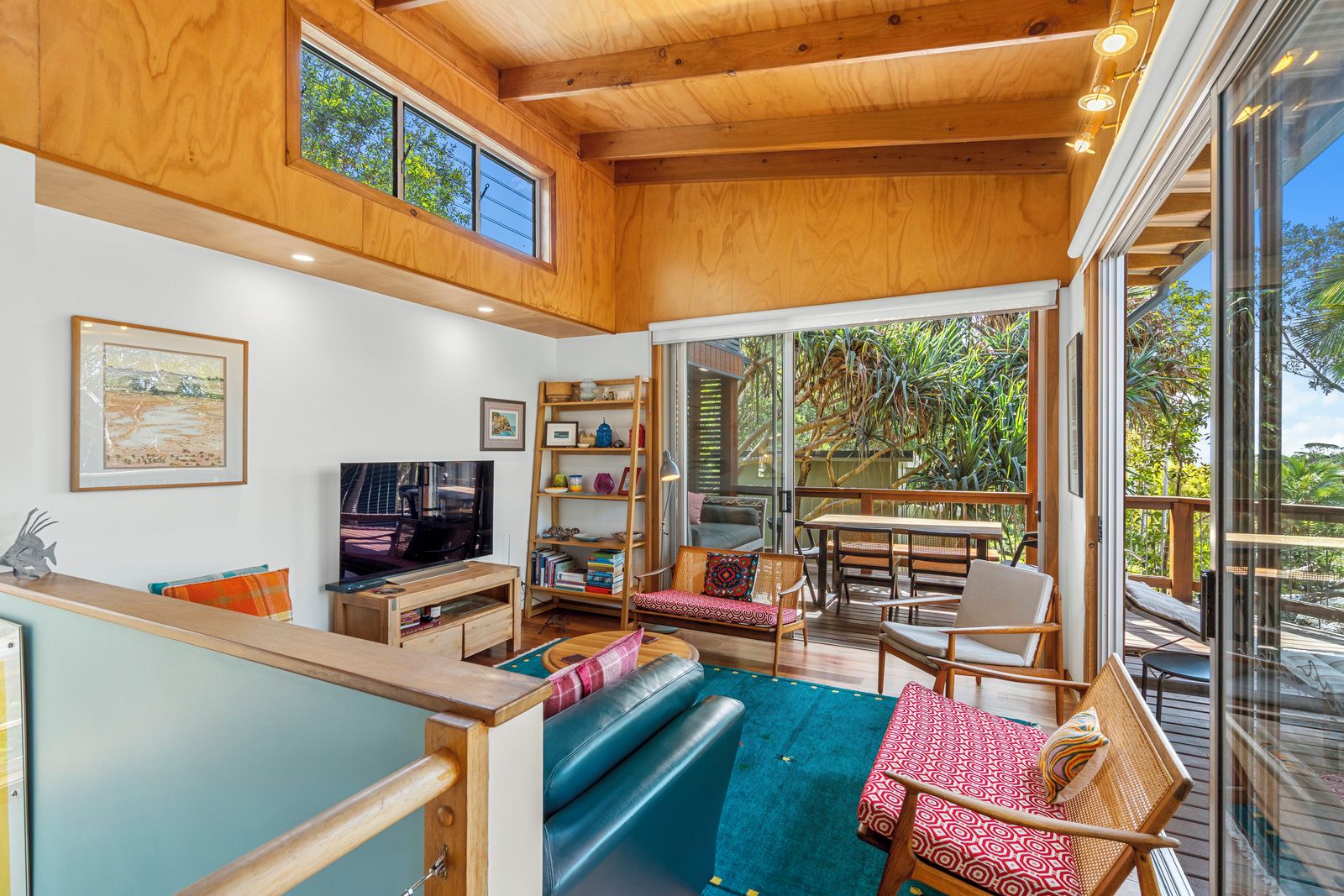 A spacious living area with a television, bookshelves, and a dining table.
