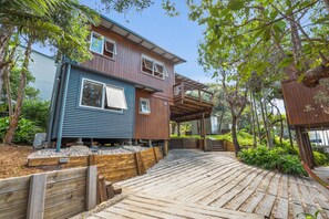 A two-story house with a wooden deck leading to a covered outdoor area.